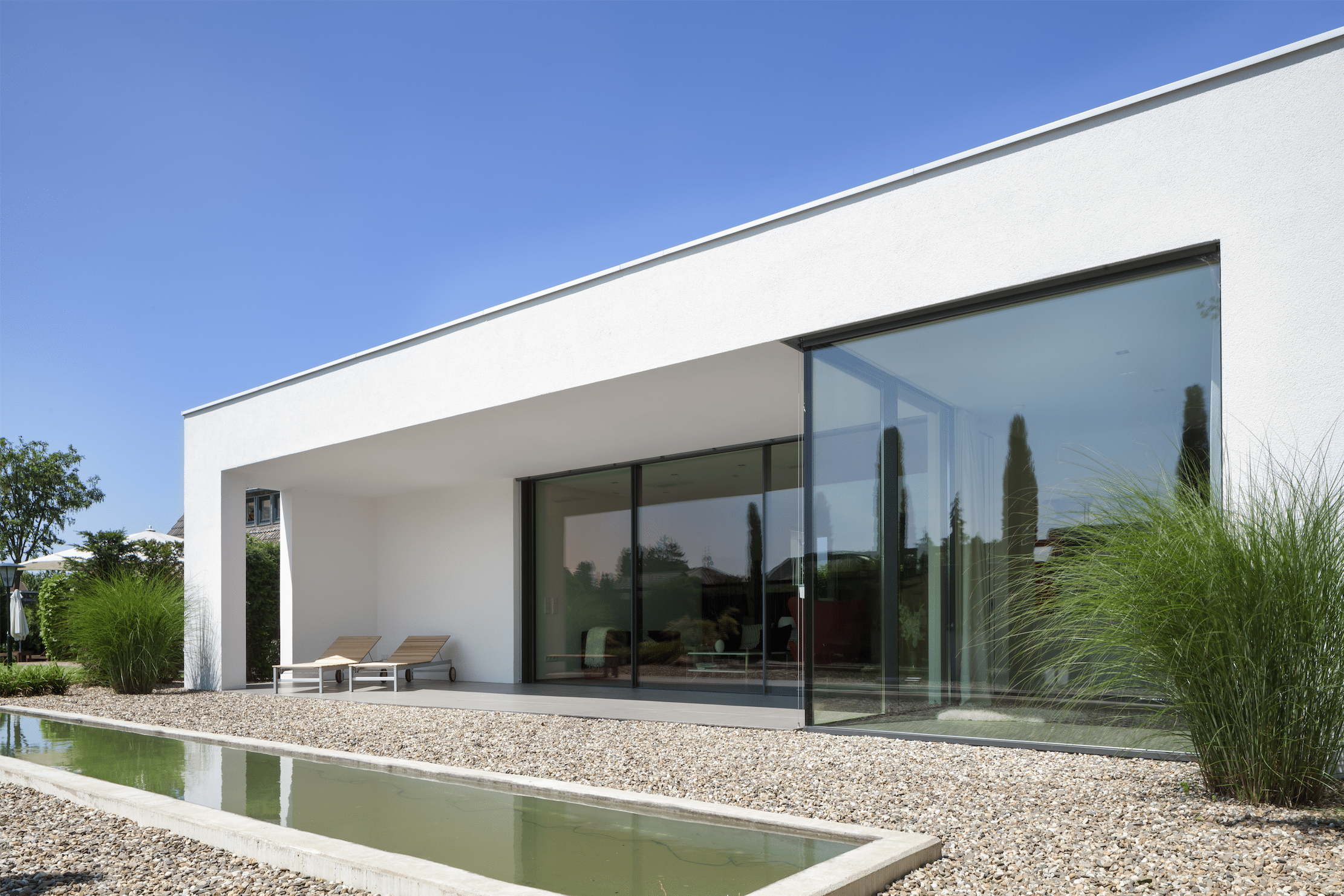Bungalow mit Pool, großer Terrasse und barrierefreiem, großzügigem Übergang zum Wohnraum dank deckenhoher Glasfronten, bestehend aus Glasschiebetüren von Solarlux.