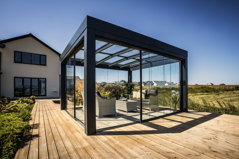 Holzterrasse mit rundum verglastem Wintergarten Cubus mit rahmenlosen Solarlux Schiebetüren und Glasdach.