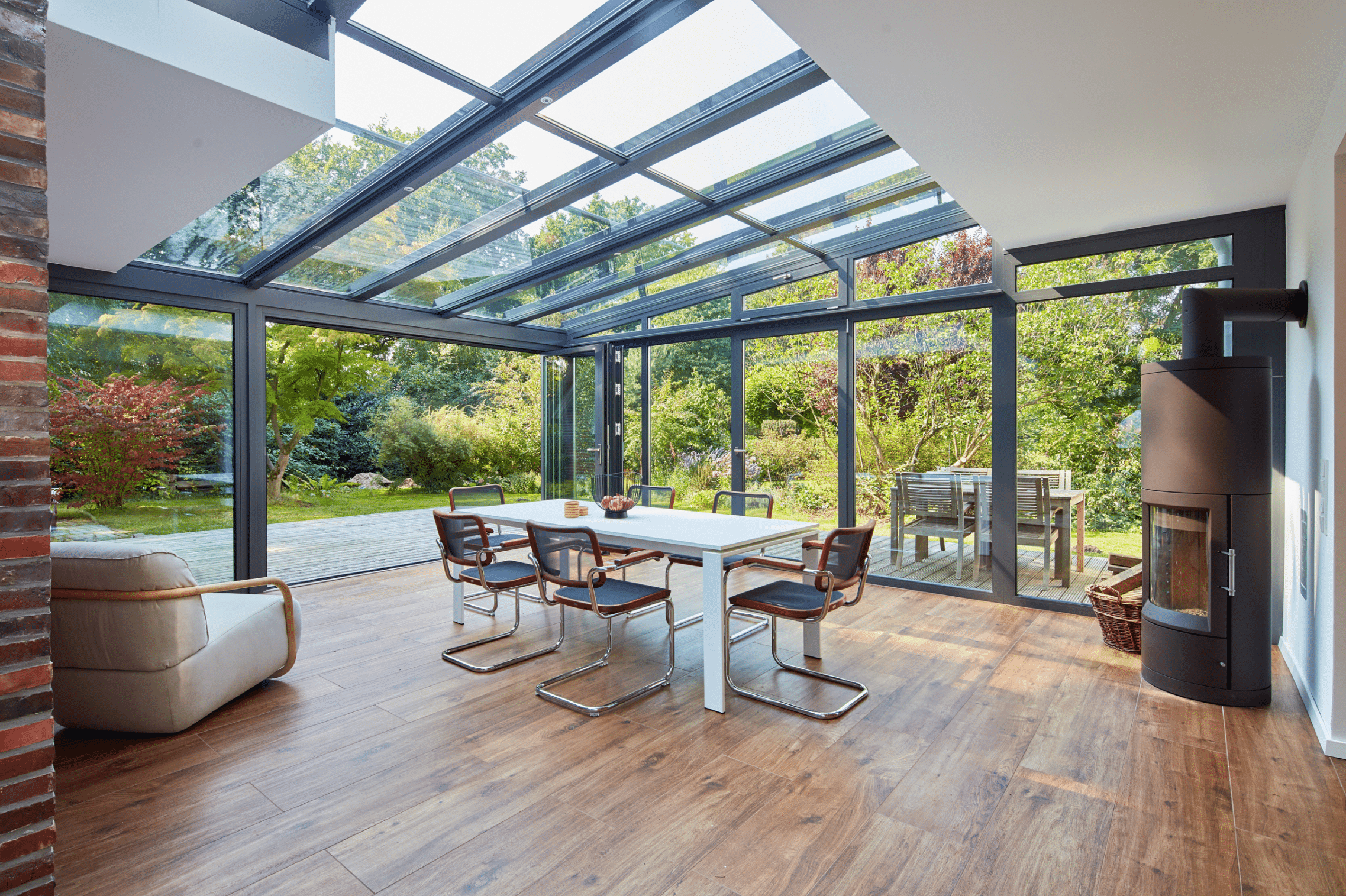 Schöner, heller Wintergarten-Anbau mit Panoramablick in den Garten dank deckenhoher Glasschiebetüren und teilweisem Glasdach von Solarlux.