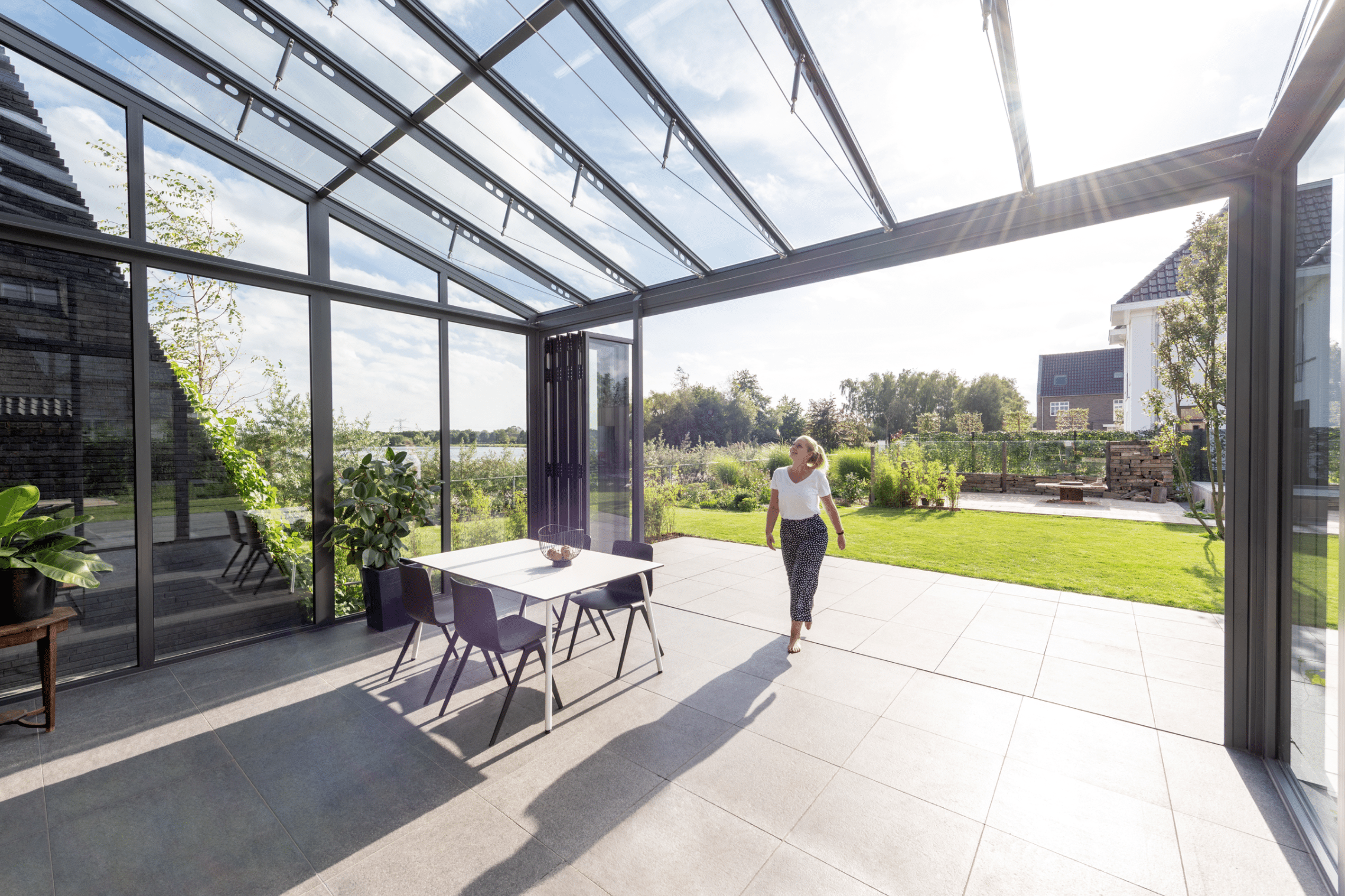 Wintergarten mit barrierefreiem Zugang zum Garten, deckenhohen Glasfalttüren und einem Glasdach von Solarlux.