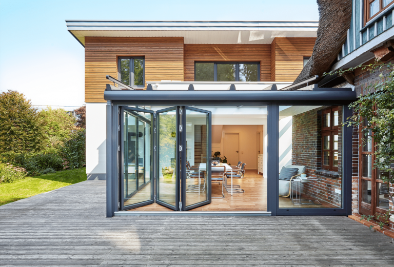 Wintergarten mit Panoramablick in den Garten, deckenhohen Glasfalttüren und einem Glas-Terrassendach von Solarlux.