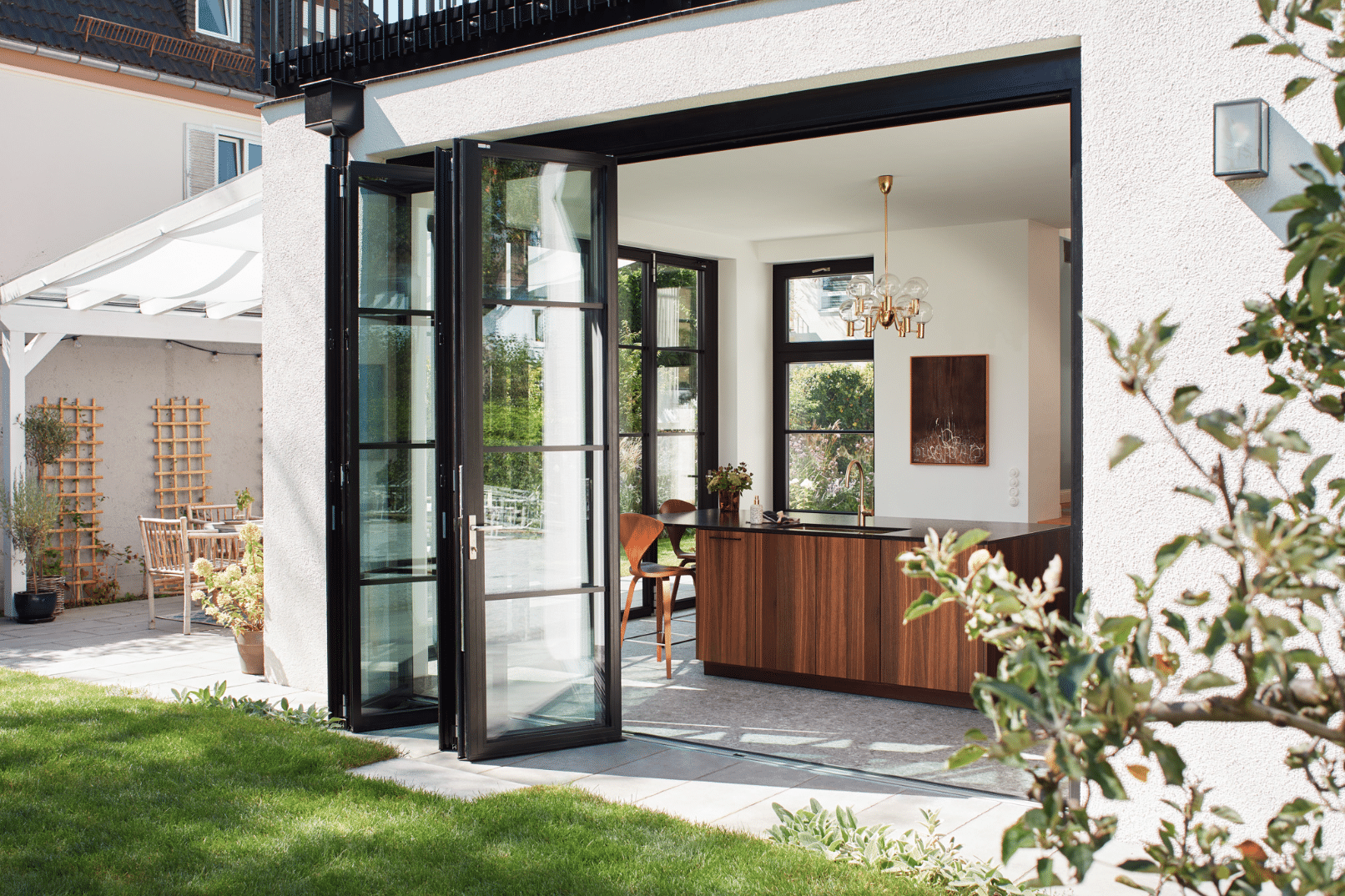 Solarlux zeigt ein Einfamilienhaus mit zum Garten hin orientierter Küche mit Glasfalttüren im französischen Stil.