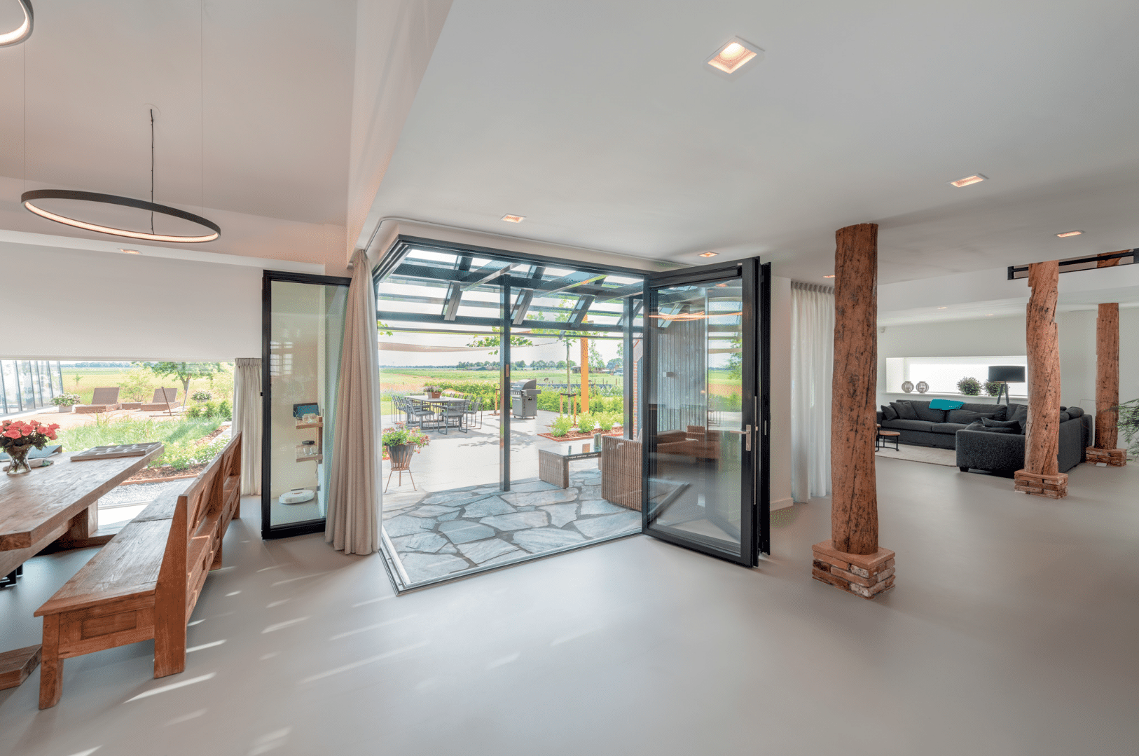 Solarlux zeigt ein offenes Wohn-/Esszimmer mit großen Glasfalttüren.