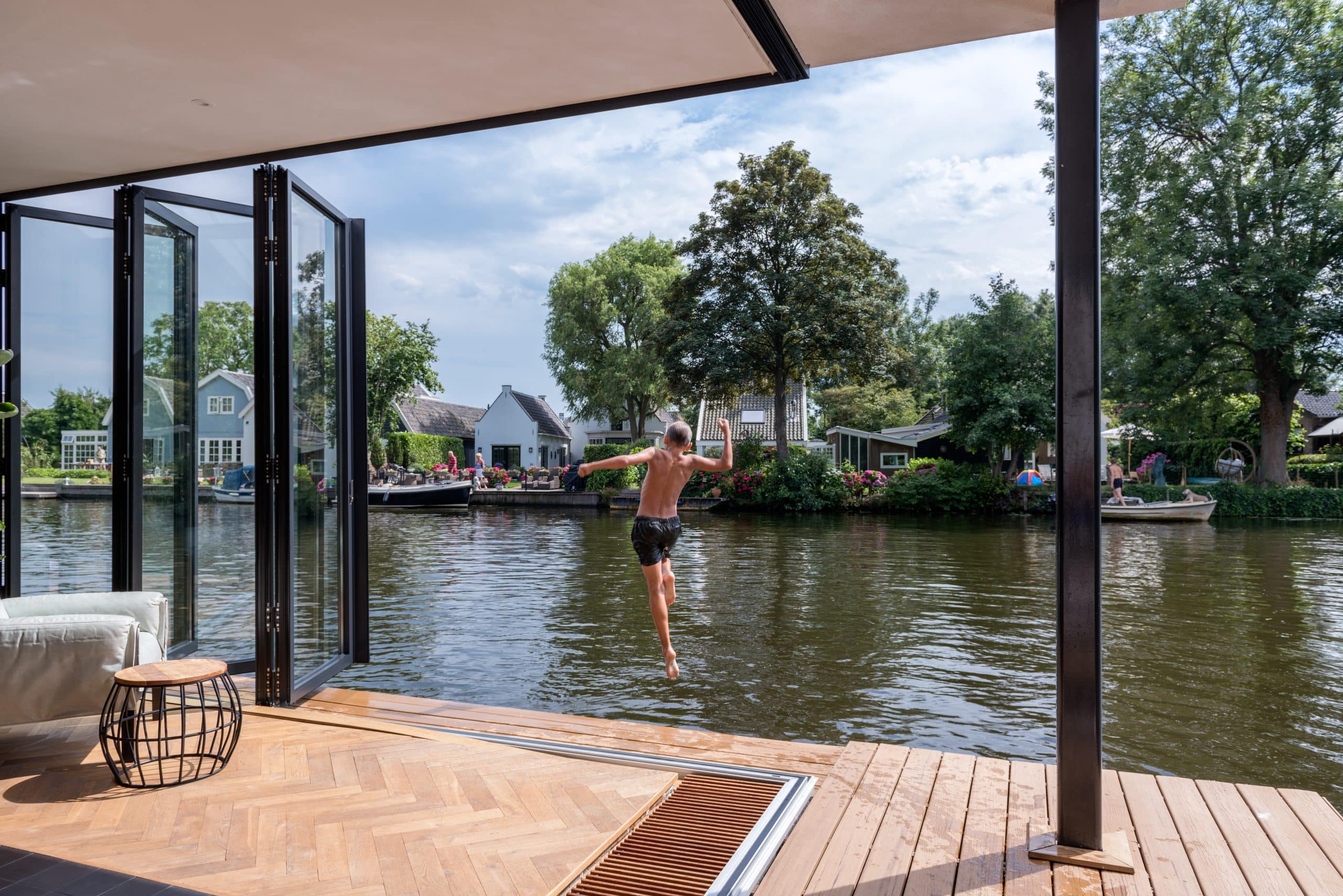 Solarlux zeigt ein Esszimmer mit Glasfaltwand wodurch man direkt auf ein Boot oder in den Teich gelangt.