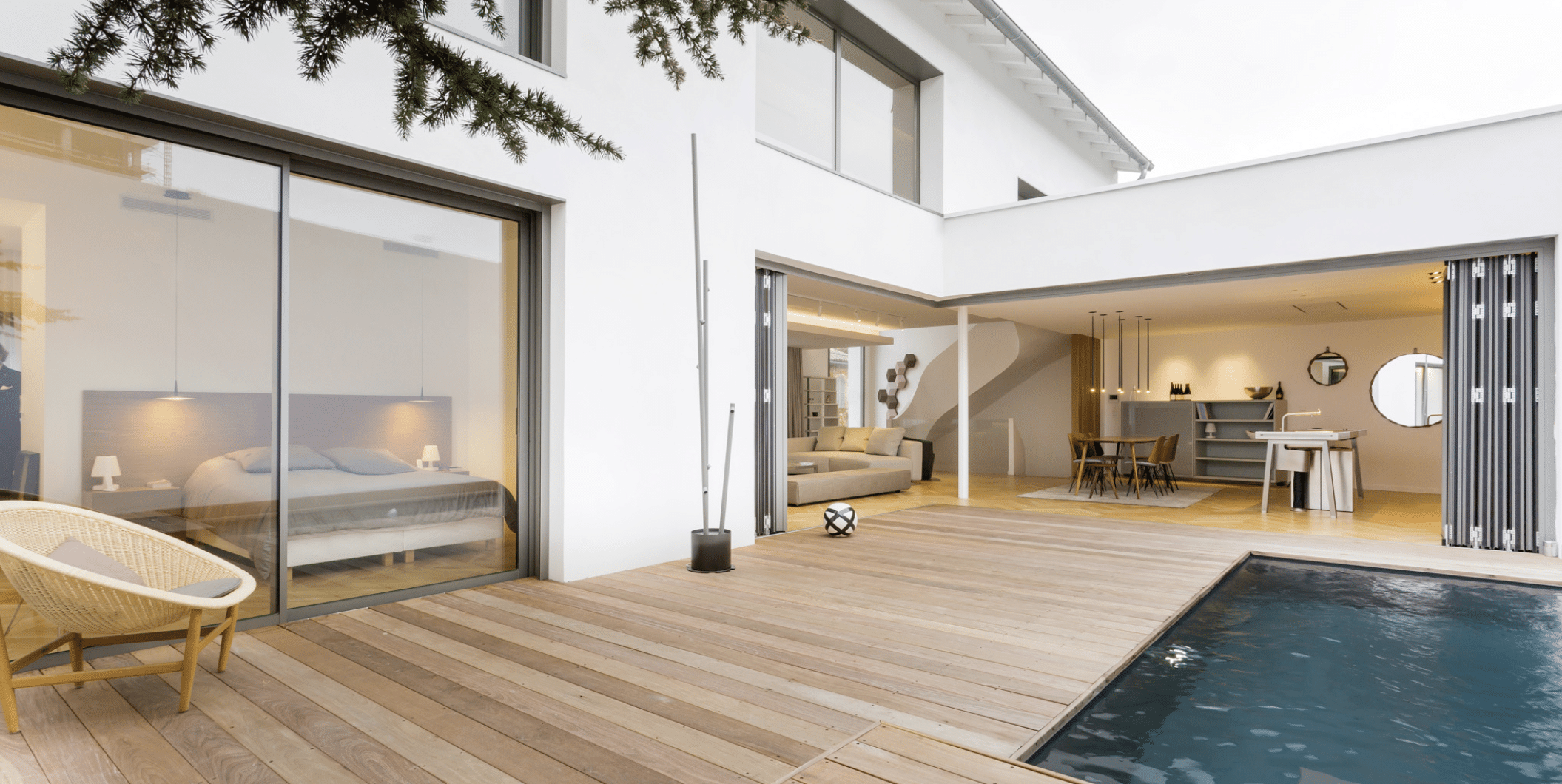 SOLARLUX präsentiert das übers Eck gehende Glasfaltfenster eines Einfamilienhauses mit Pool, Holzverbau rundherum und Zugang zur Küche und Wohnbereich.