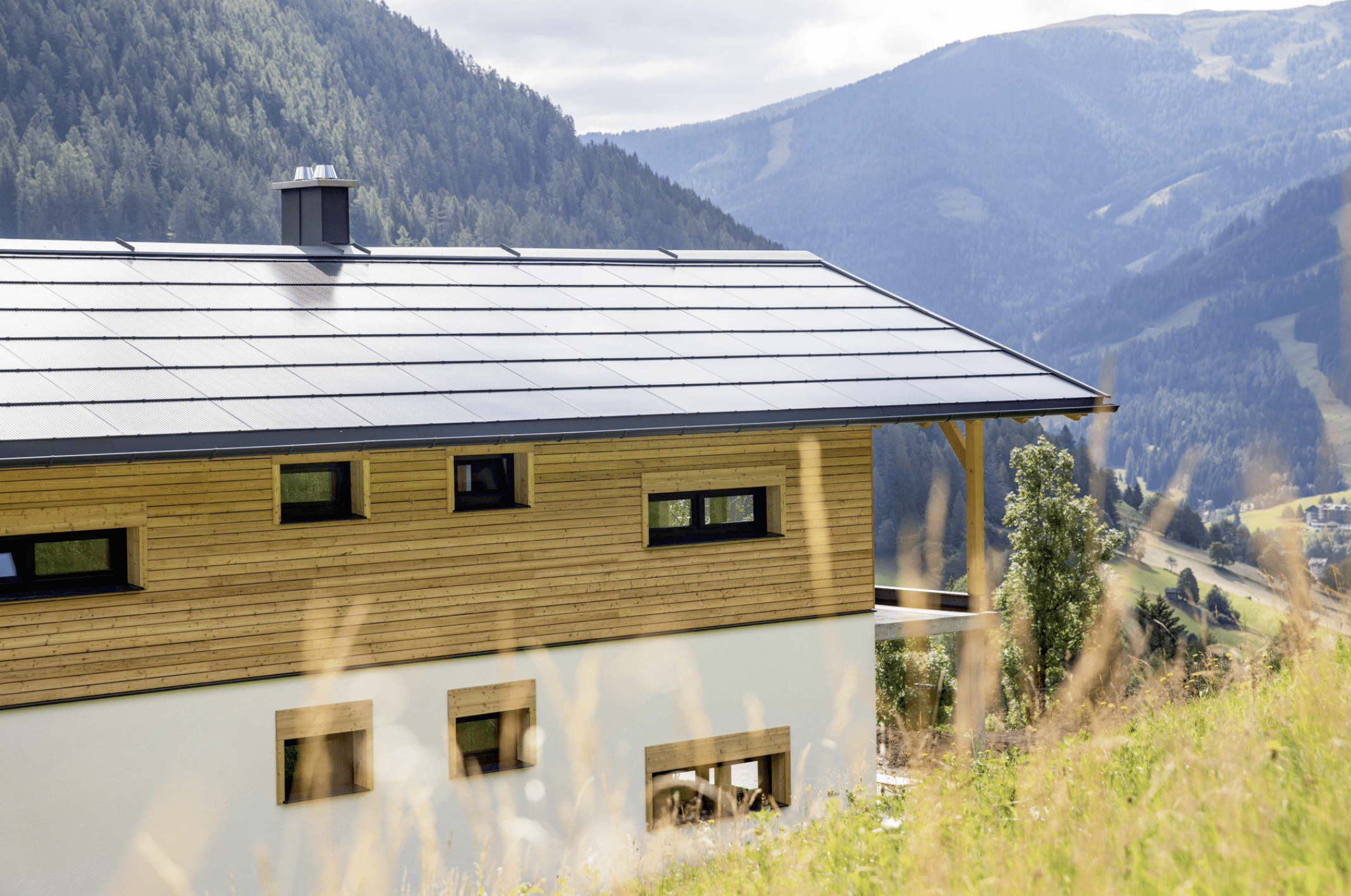 SONNENKRAFT zeigt eine auf dem Dach montierte Photovoltaikanlage eines modernem Hauses in den Bergen.