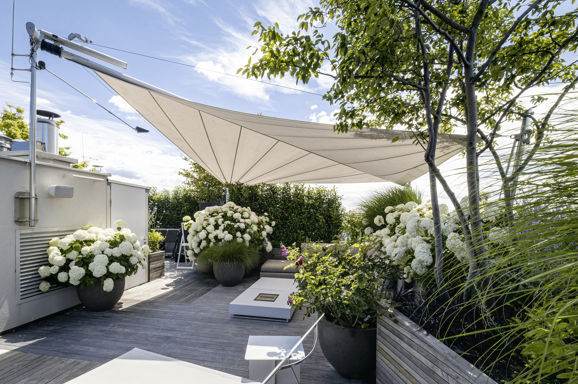 Dachterrasse mit vielen Blumen und modernem Sonnensegel von SunSquare.