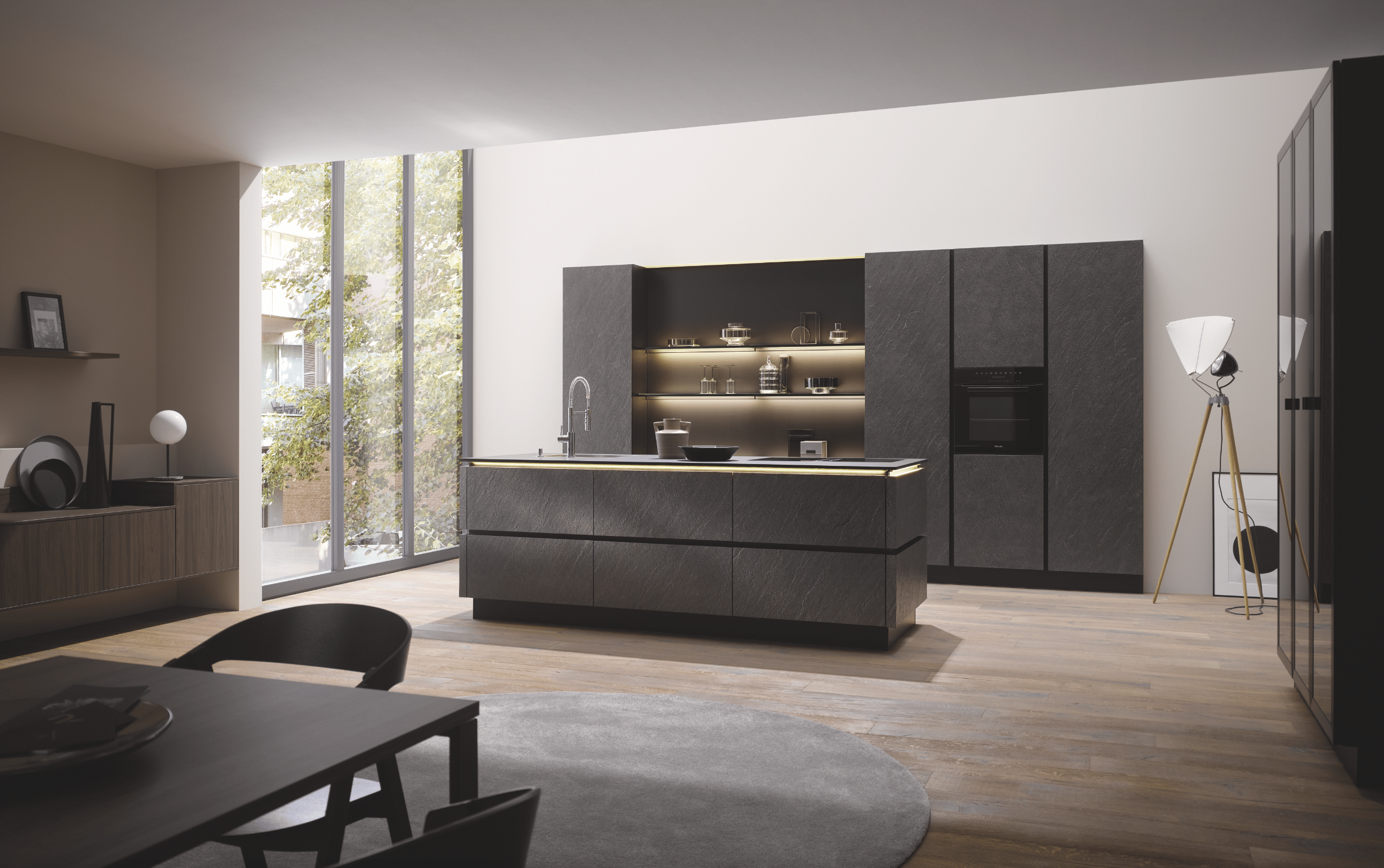 Tischlerei Bauer zeit eine moderne Küche mit Holzboden und einer Kücheninsel in dunklem grau mit Spülbecken und großem Einbauschrank mit integriertem Backofen von Häcker Küchen.