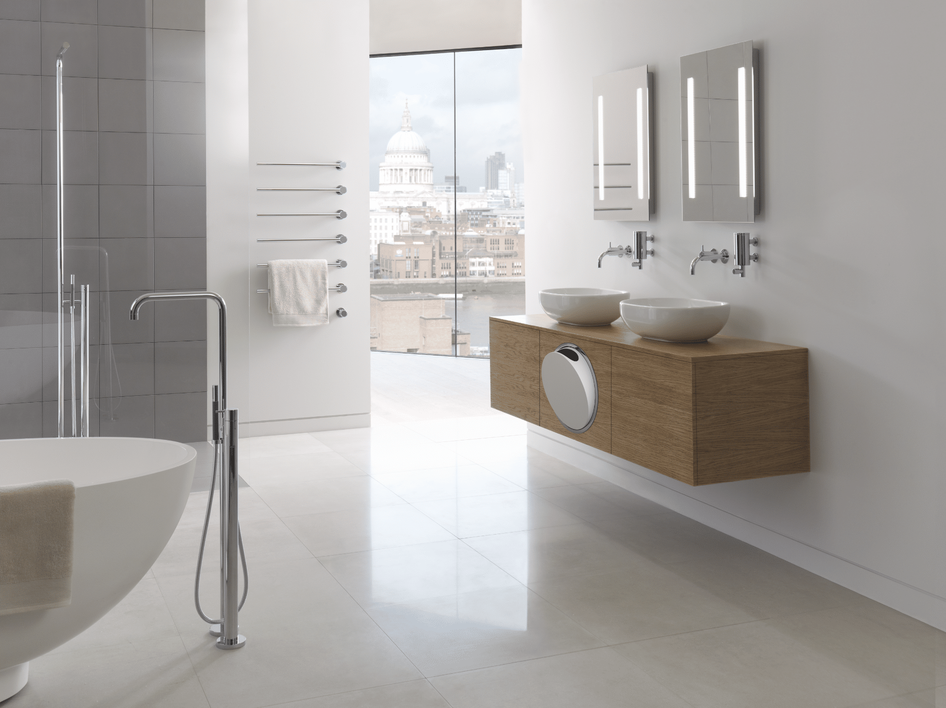 VOLA zeigt ein lichtdurchflutetes Badezimmer mit hellem Fliesenboden, einem Doppelwaschtisch aus Holz und einer freistehenden Badewanne neben einer ebenerdigen Duschkabine mit Glastüren.
