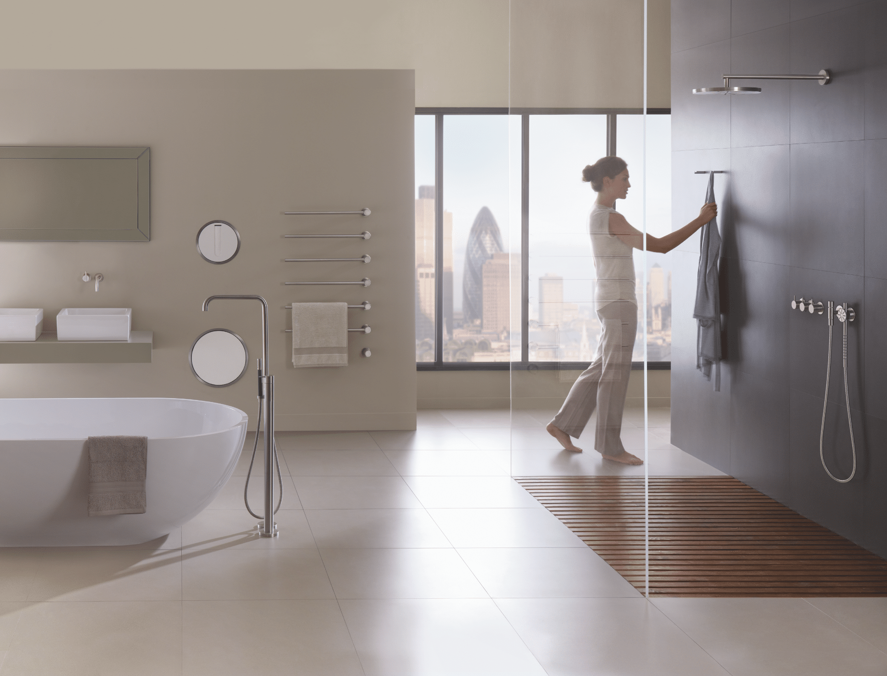 VOLA zeigt ein Badezimmer mit hellem Fliesenboden, einem Doppelwaschtisch mit eckigen Waschbecken und einer freistehenden Badewanne neben einer ebenerdigen Duschkabine mit Glaswänden.