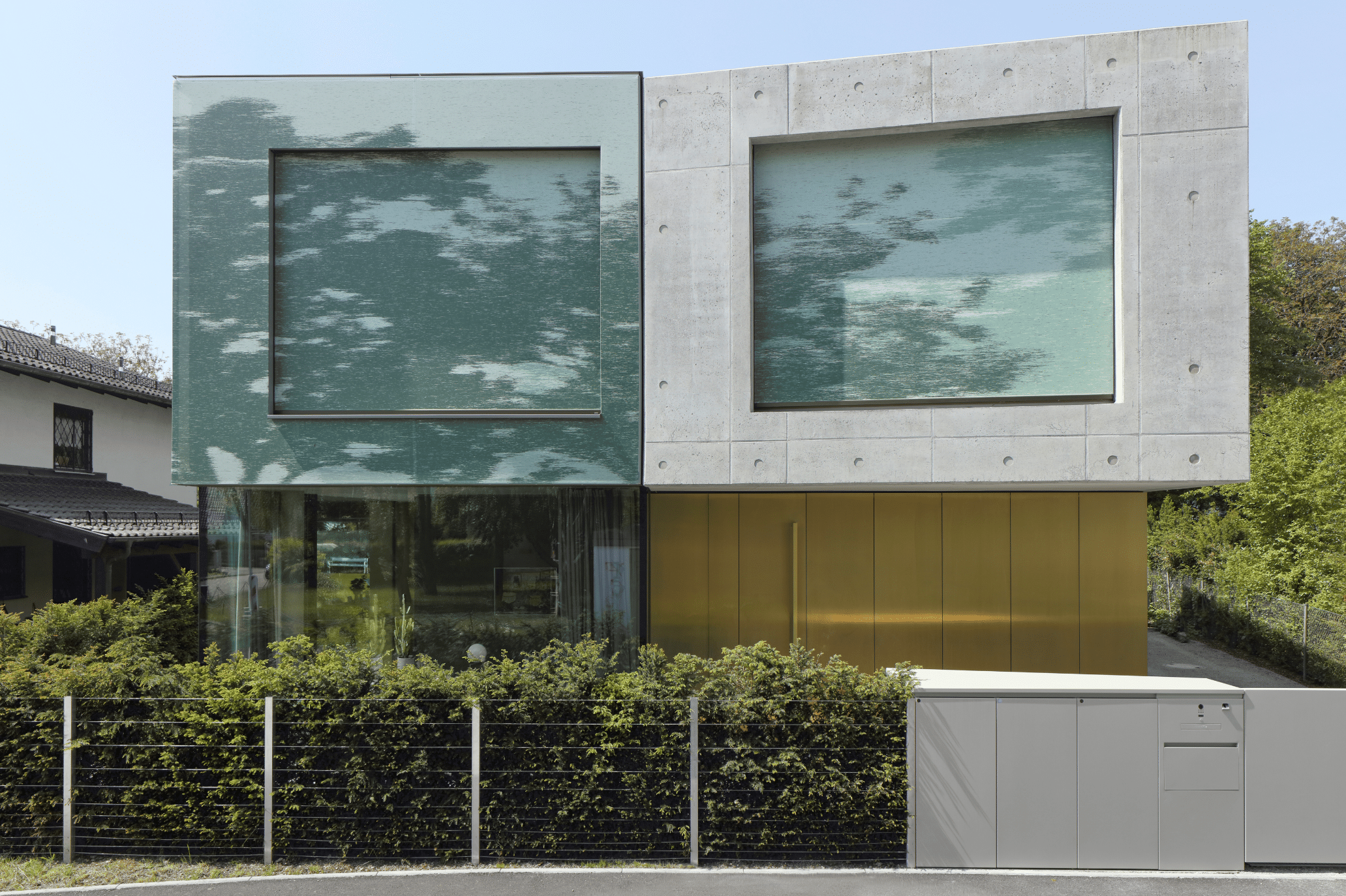 Im geschlossenen Zustand erweckt die ineinander übergehende Kombination aus dem bedruckten Textilumhang und den daran angepassten Fenstermarkisen den Eindruck eines natürlichen Schattenwurfes der Bäume auf die gesamte obere Hausfassade.
