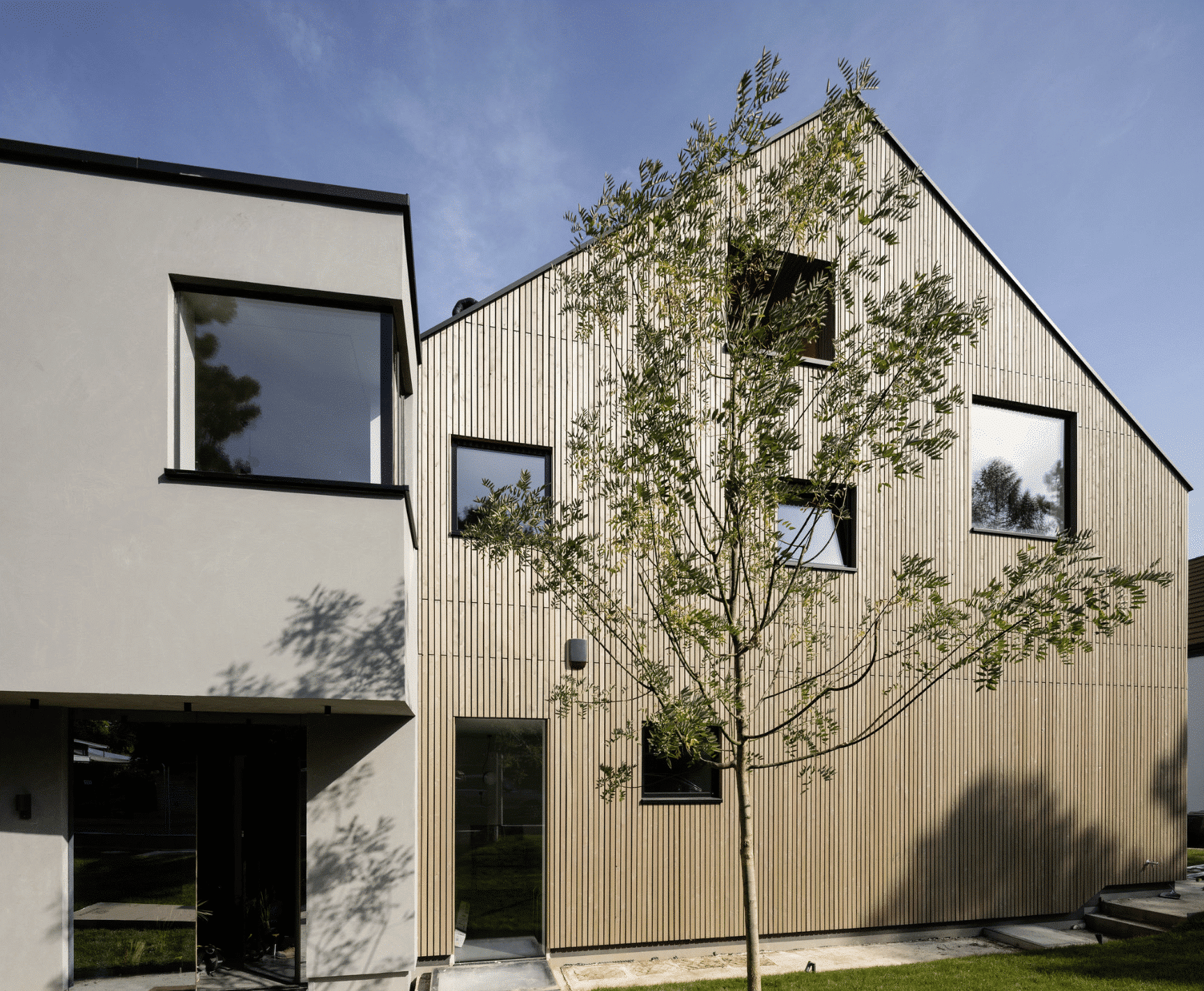 Weissenseer Holz-System-Bau zeigt modernes Satteldach Wohnhaus mit Holzverkleidung.