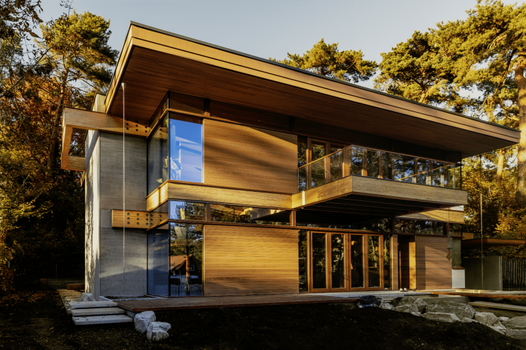 Modernes Flachdachhaus mit bodentiefer Fixverglasung, Balkon, Terrasse und Holzfassade von Weissenseer Holz-System-Bau.