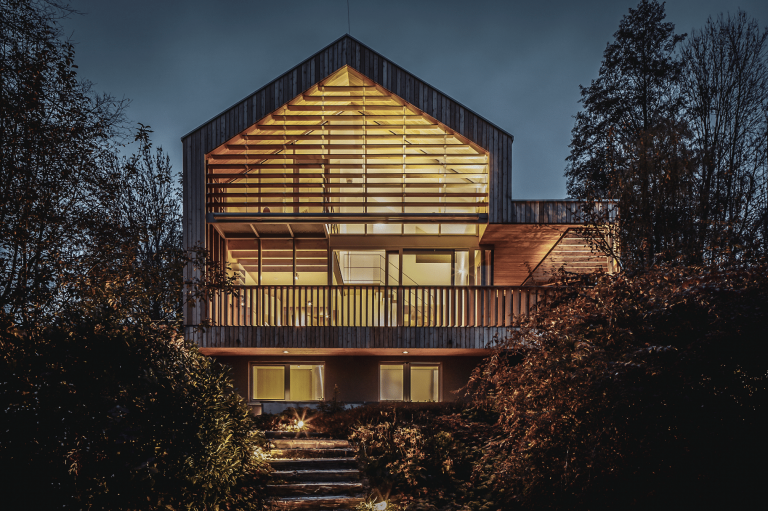 Einfamilienhaus mit Satteldach und Holzfassade bei Nacht von Weissenseer Holz-System-Bau.