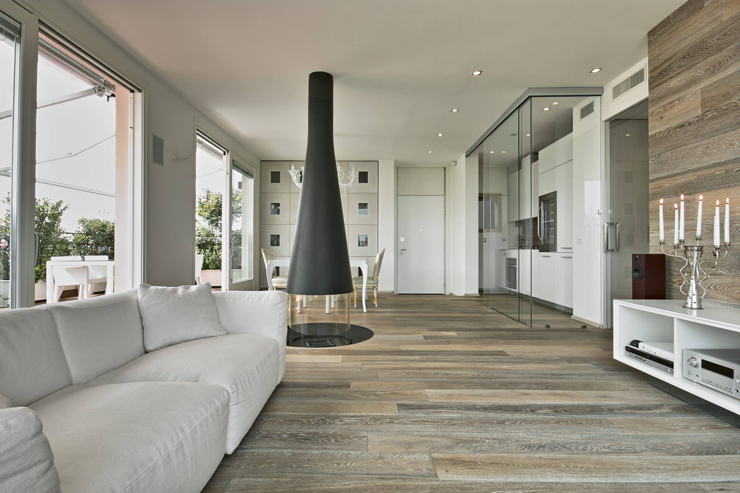Offener Wohnraum mit freistehendem Kamin und elegantem Parkettboden.